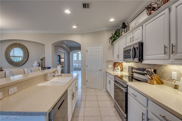 kitchen featuring stainless steel appliances, white cabinets, sink, ornamental molding, and light tile patterned flooring