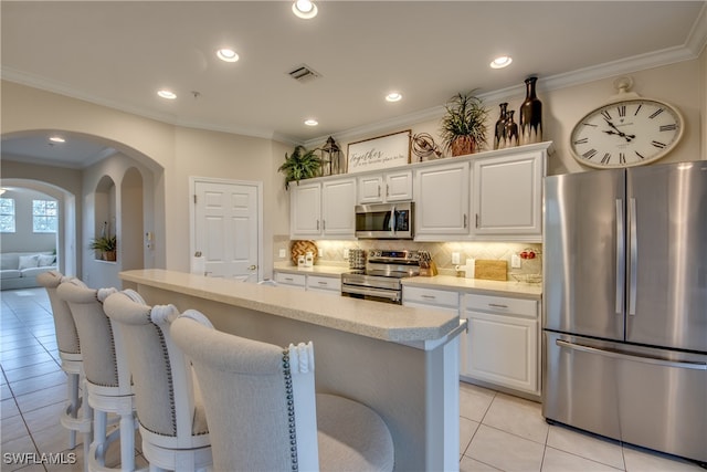 kitchen featuring white cabinets, appliances with stainless steel finishes, backsplash, and an island with sink