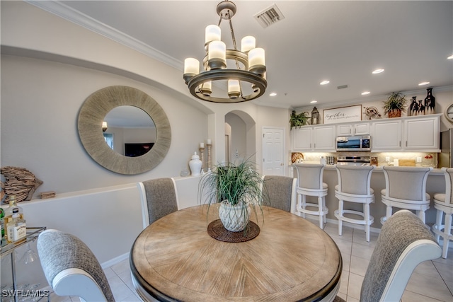 tiled dining room featuring an inviting chandelier and crown molding