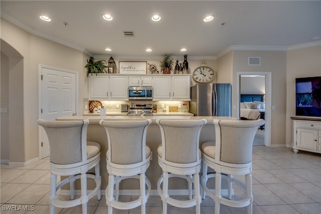 kitchen with ornamental molding, stainless steel appliances, white cabinetry, backsplash, and a large island