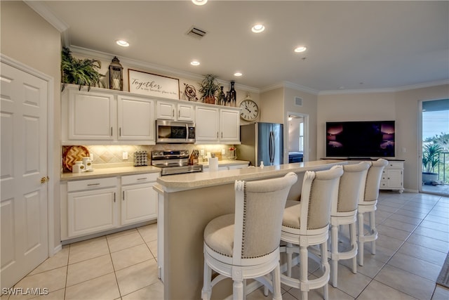 kitchen featuring white cabinets, stainless steel appliances, a breakfast bar area, and a center island