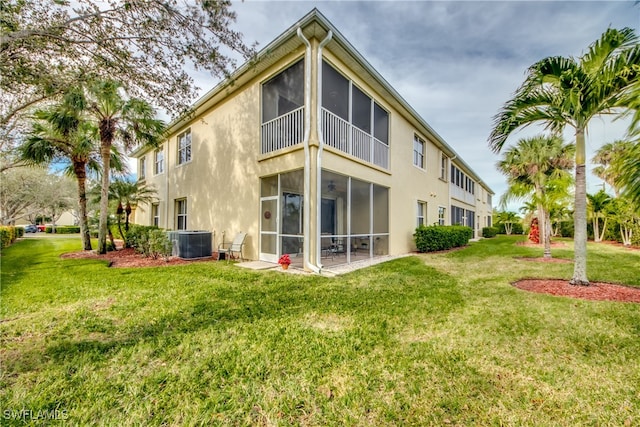 back of property with central AC unit, a lawn, and a sunroom