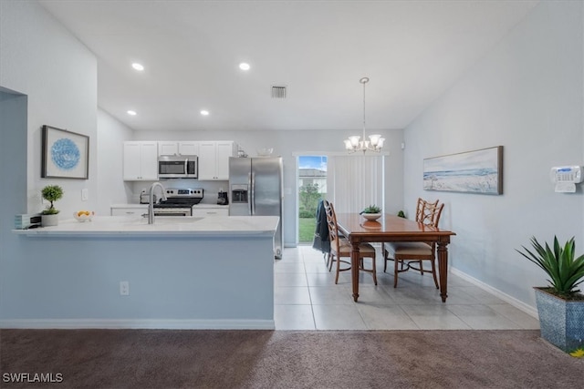 kitchen with appliances with stainless steel finishes, pendant lighting, white cabinets, kitchen peninsula, and light colored carpet