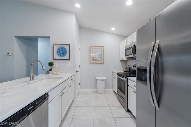 kitchen featuring lofted ceiling, light tile patterned flooring, light stone countertops, white cabinetry, and appliances with stainless steel finishes