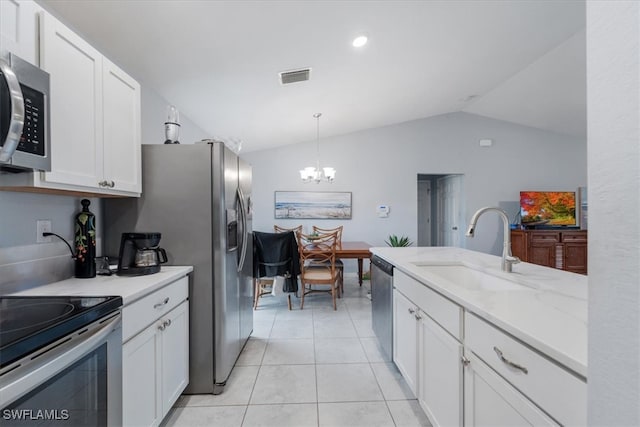 kitchen featuring stainless steel appliances, vaulted ceiling, white cabinets, sink, and decorative light fixtures