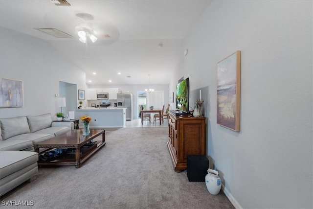 carpeted living room featuring high vaulted ceiling and ceiling fan with notable chandelier