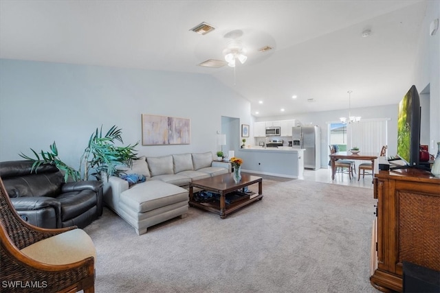 carpeted living room with vaulted ceiling and ceiling fan with notable chandelier