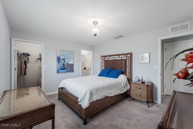 carpeted bedroom with ensuite bathroom, a walk in closet, and a closet