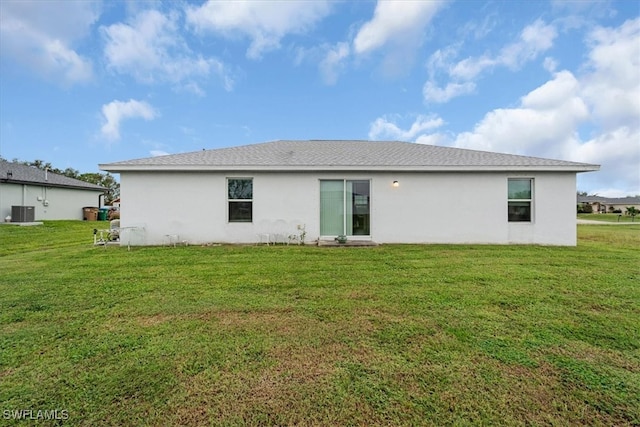 back of house featuring central AC unit and a yard