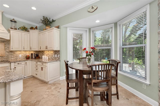 kitchen with crown molding, light stone countertops, backsplash, and a wealth of natural light