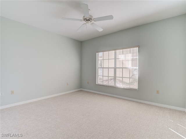 carpeted spare room featuring ceiling fan and baseboards