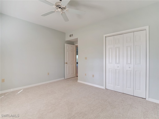 unfurnished bedroom featuring a closet, visible vents, a ceiling fan, light carpet, and baseboards