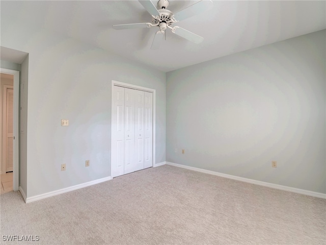 unfurnished bedroom featuring light carpet, ceiling fan, baseboards, and a closet