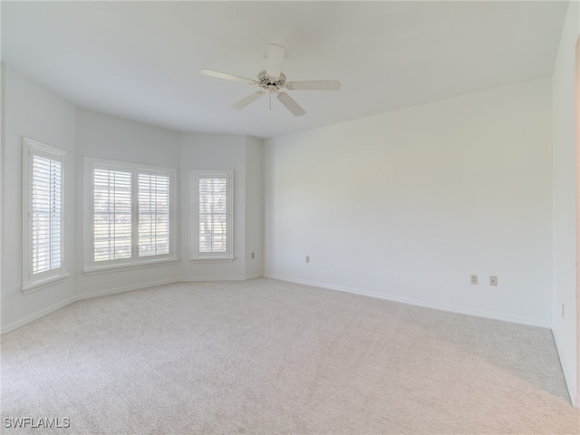 spare room featuring baseboards, plenty of natural light, a ceiling fan, and light colored carpet