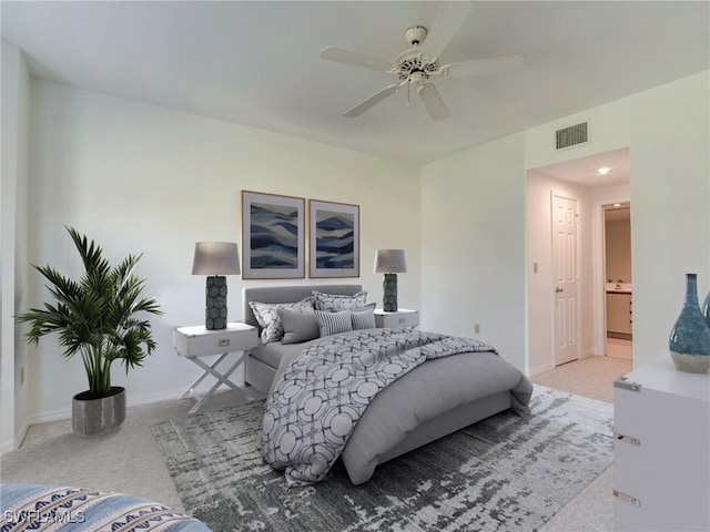 carpeted bedroom featuring a ceiling fan, ensuite bath, visible vents, and baseboards