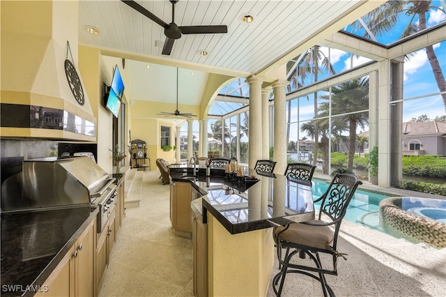 sunroom featuring ceiling fan, wooden ceiling, and sink