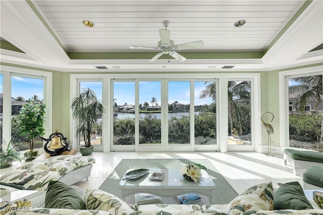 sunroom featuring ceiling fan, a water view, and a raised ceiling