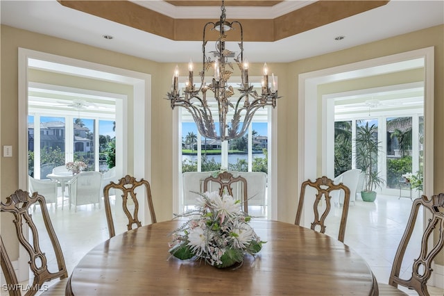 dining room with light tile patterned floors, a wealth of natural light, ceiling fan with notable chandelier, and a tray ceiling