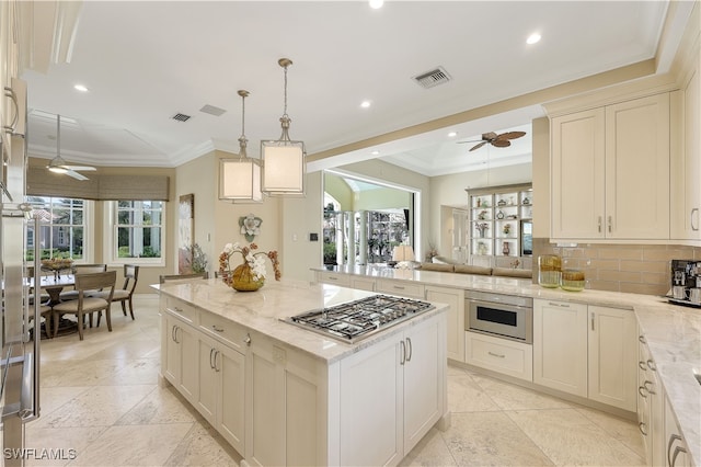 kitchen featuring hanging light fixtures, stainless steel gas cooktop, ornamental molding, light stone counters, and a kitchen island