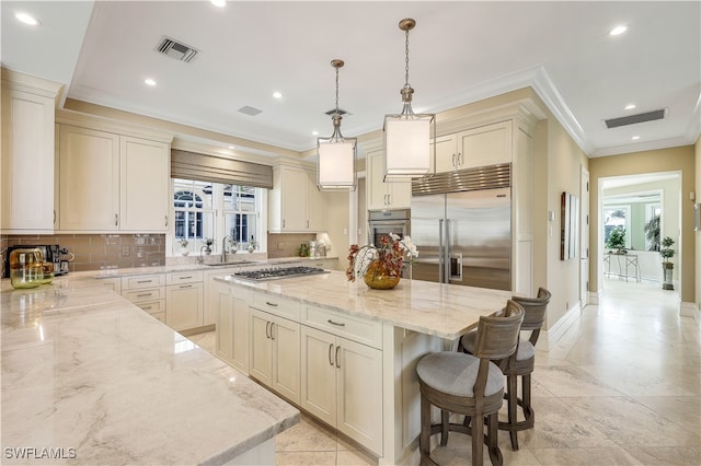 kitchen with a kitchen island, stainless steel appliances, decorative light fixtures, and light stone countertops