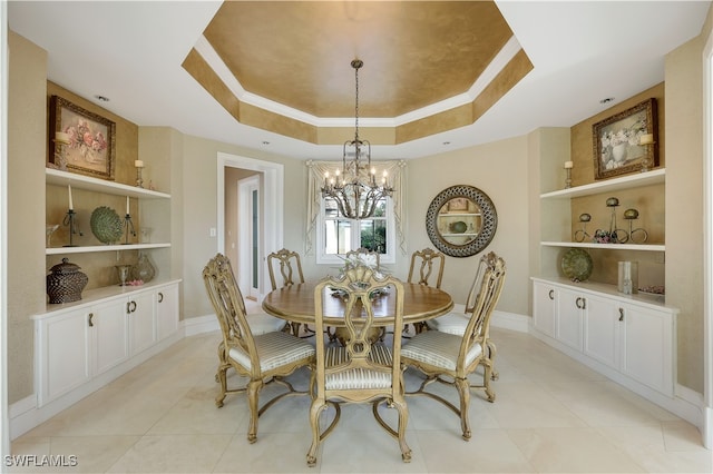 tiled dining space with ornamental molding, an inviting chandelier, built in features, and a raised ceiling