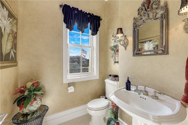 bathroom with toilet, tile patterned floors, and sink