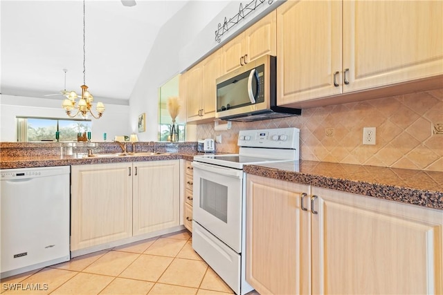 kitchen with white appliances, vaulted ceiling, sink, light tile patterned floors, and an inviting chandelier