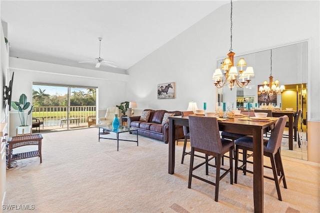 dining room with ceiling fan with notable chandelier, light colored carpet, and high vaulted ceiling