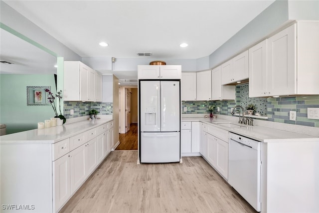 kitchen with sink, white appliances, decorative backsplash, white cabinets, and light wood-type flooring