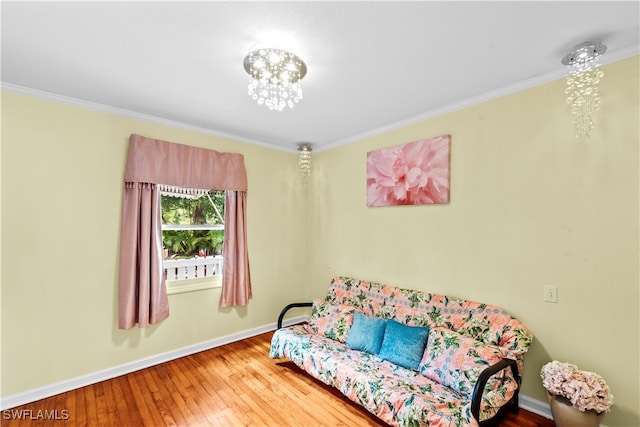 living area with wood-type flooring, an inviting chandelier, and crown molding