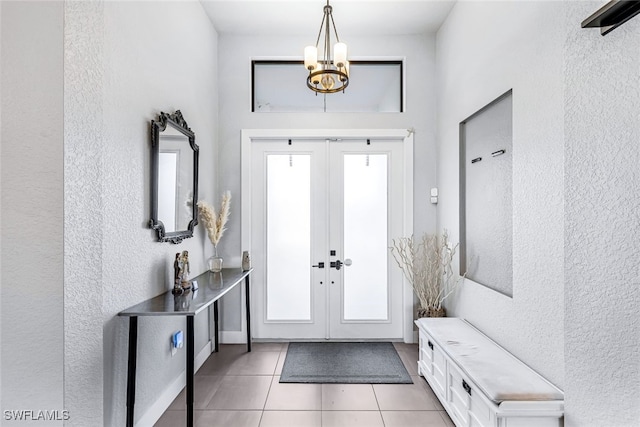 tiled foyer entrance with french doors and a notable chandelier