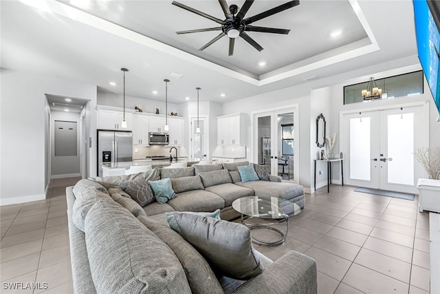 living room featuring ceiling fan, light tile patterned flooring, a tray ceiling, and french doors