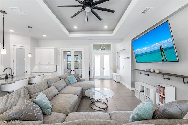 living room with french doors, a tray ceiling, ceiling fan, sink, and light tile patterned flooring