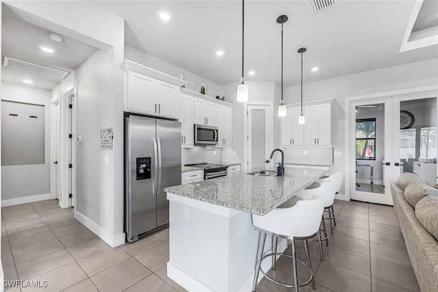 kitchen featuring light stone countertops, sink, tasteful backsplash, white cabinets, and appliances with stainless steel finishes