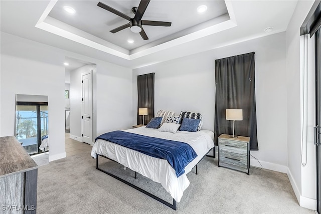 carpeted bedroom featuring a raised ceiling and ceiling fan