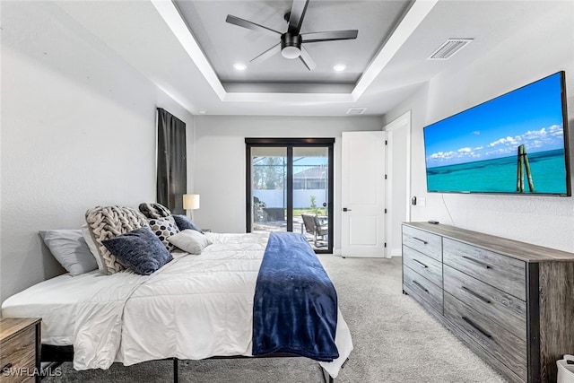 bedroom with access to exterior, light carpet, a tray ceiling, and ceiling fan