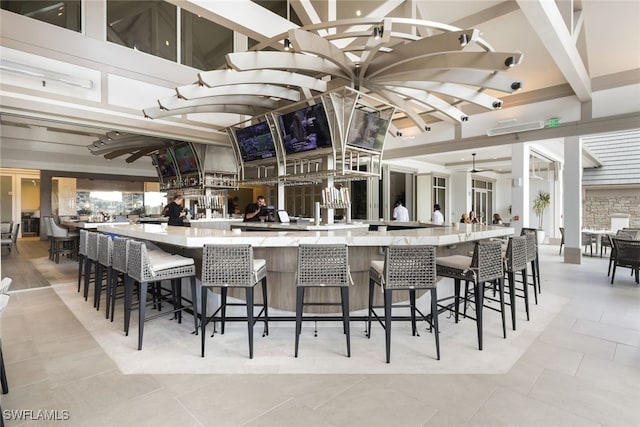 kitchen featuring vaulted ceiling with beams, light tile patterned floors, and a breakfast bar