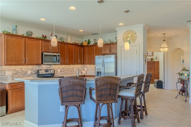 kitchen featuring decorative light fixtures, a center island, ornamental molding, and appliances with stainless steel finishes