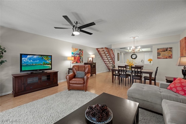 living room featuring a textured ceiling, light hardwood / wood-style floors, and ceiling fan with notable chandelier