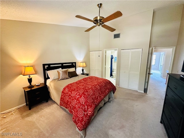 bedroom with high vaulted ceiling, light colored carpet, ceiling fan, and ensuite bath