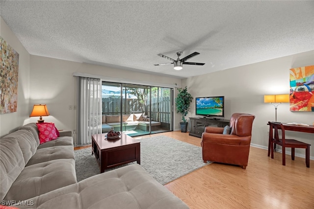 living room featuring a textured ceiling, light hardwood / wood-style flooring, and ceiling fan