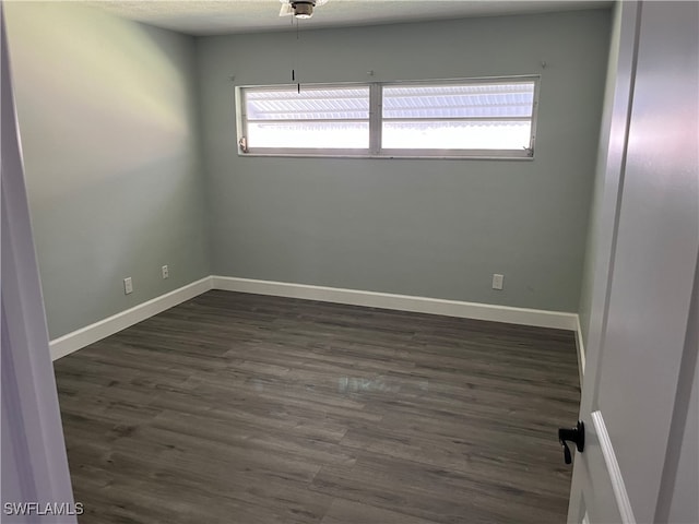 empty room featuring a textured ceiling and dark hardwood / wood-style flooring