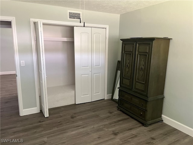 bedroom with a textured ceiling, a closet, and dark hardwood / wood-style floors