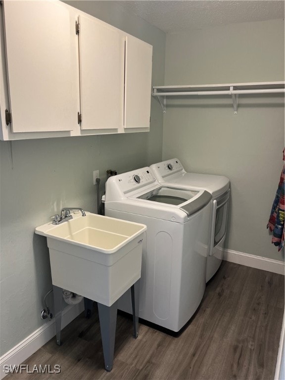 clothes washing area featuring cabinets, washing machine and dryer, and dark wood-type flooring