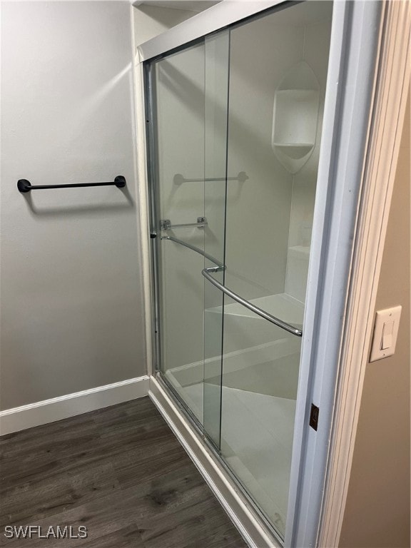 bathroom with hardwood / wood-style flooring and an enclosed shower