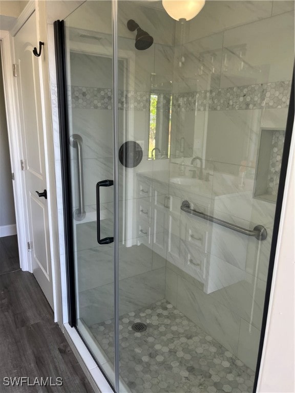 bathroom featuring wood-type flooring and a shower with shower door