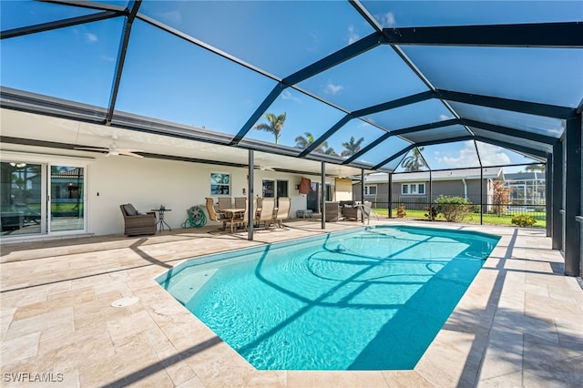 view of swimming pool with a patio, glass enclosure, and ceiling fan