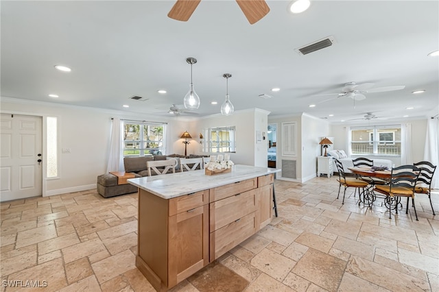 kitchen featuring light brown cabinets, a center island, hanging light fixtures, and ornamental molding