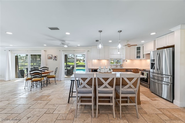 kitchen with appliances with stainless steel finishes, pendant lighting, white cabinetry, and a healthy amount of sunlight