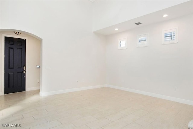 unfurnished room with arched walkways, recessed lighting, visible vents, and baseboards